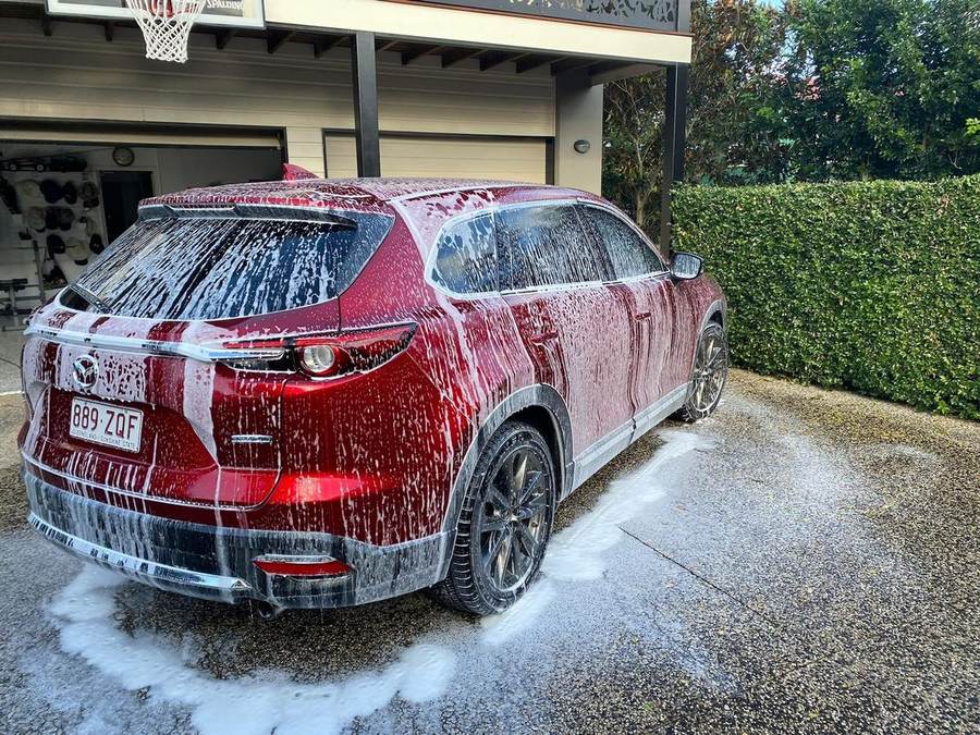Red Mazda CX-9 covered in snow foam during an exterior pre-wash